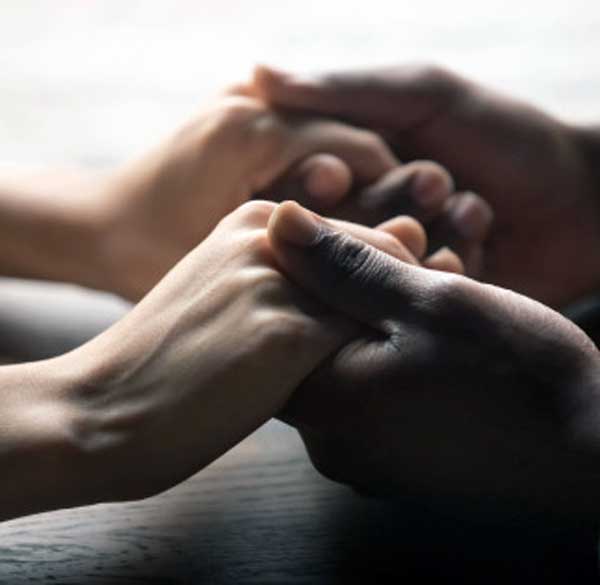 Therapist gently holding a client’s hands with warmth and empathy during a counseling session